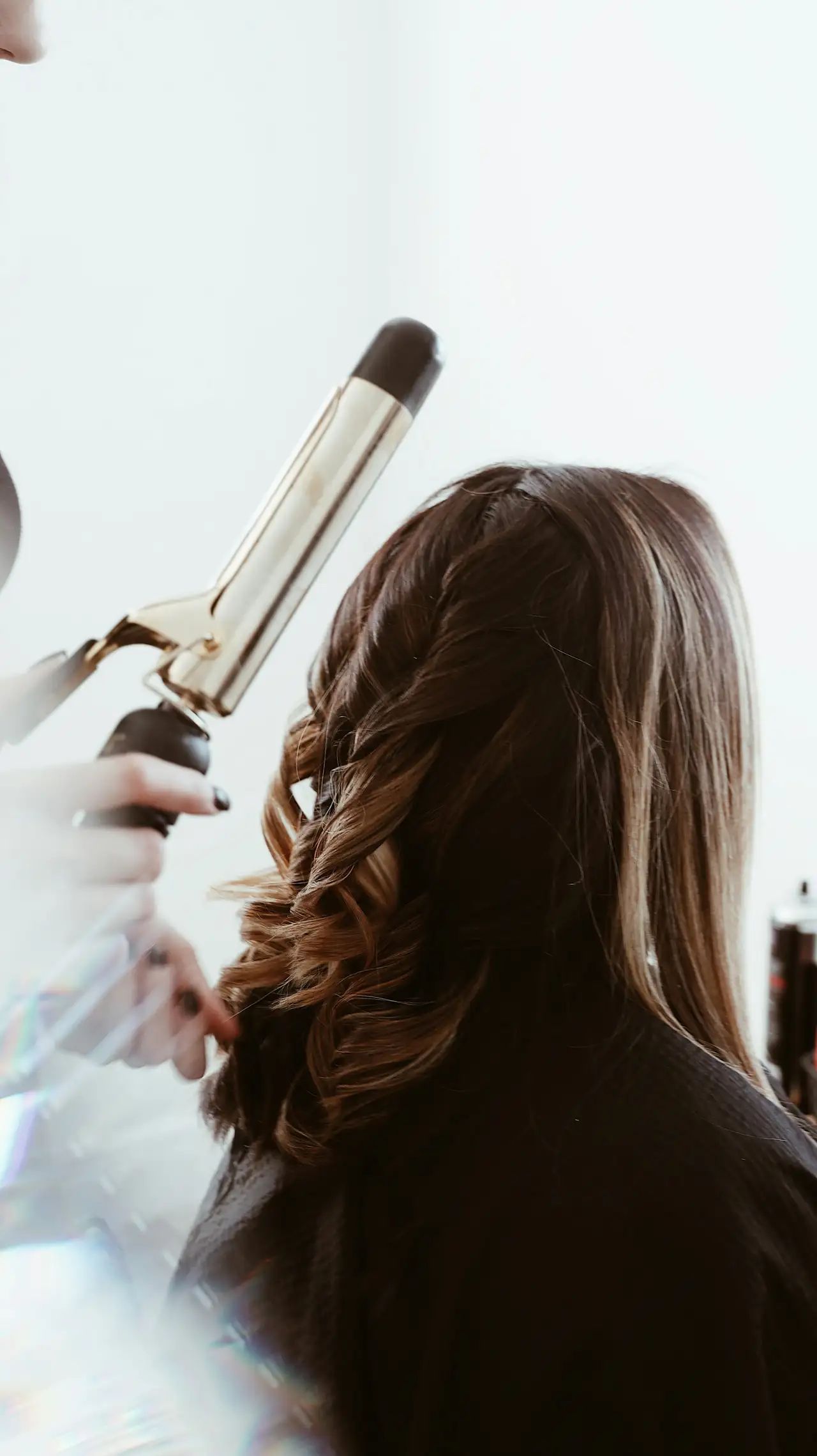 Long brown hair being curled with a tong