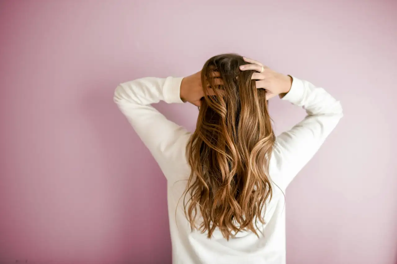 A woman seen from behind, running her hands through long waved hair