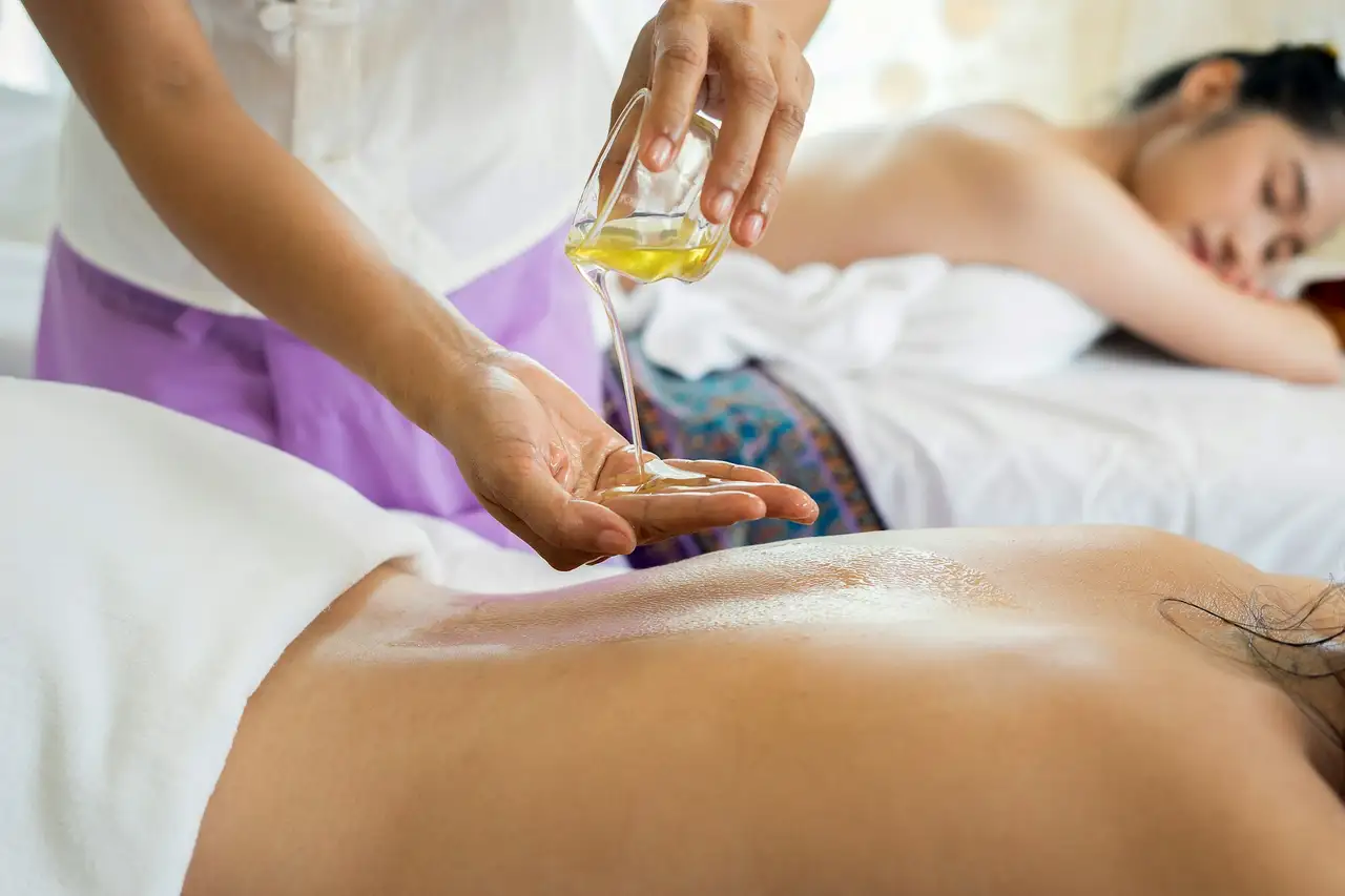 Warm oil poured onto a back during a massage