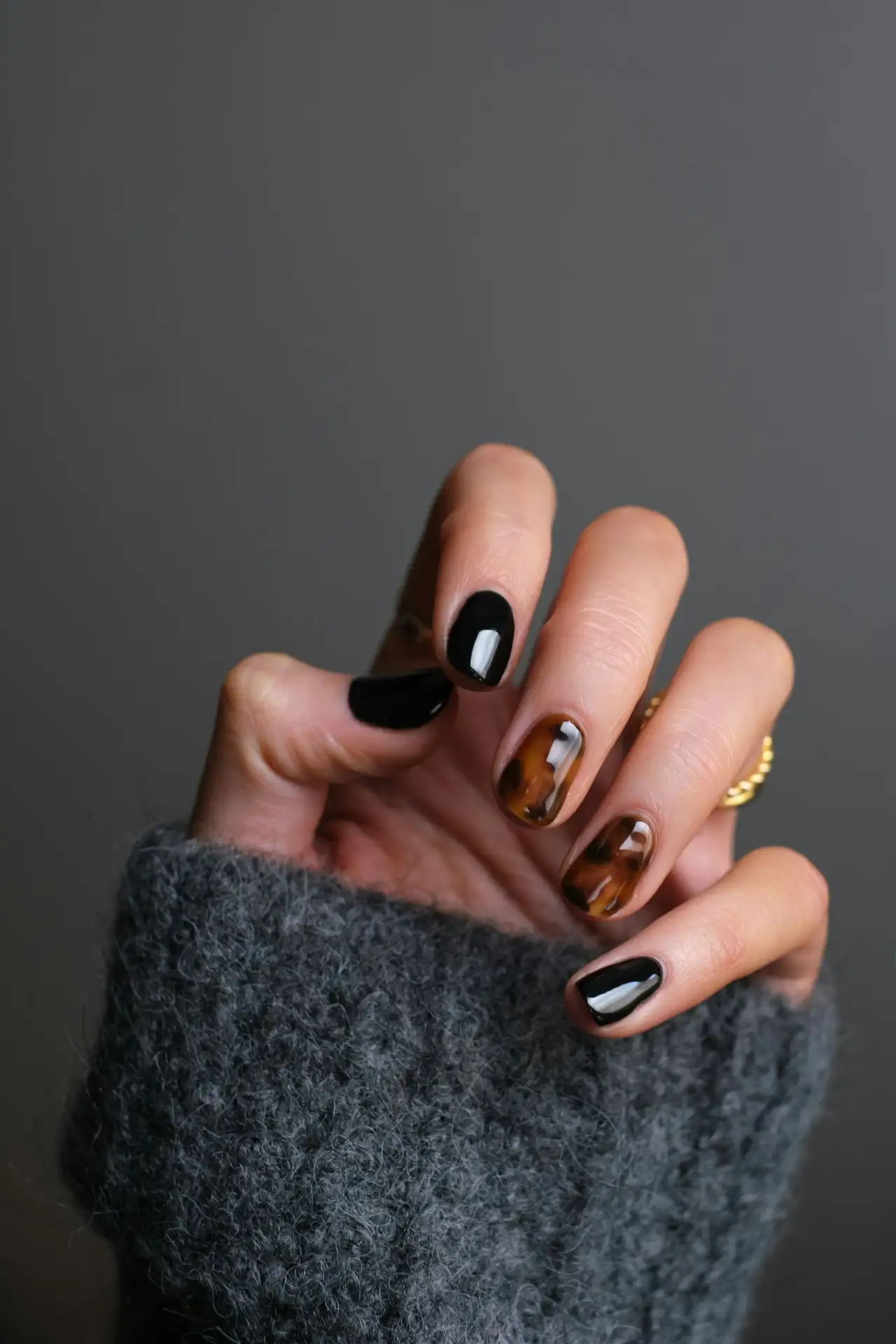A hand with dark, tortoiseshell nails