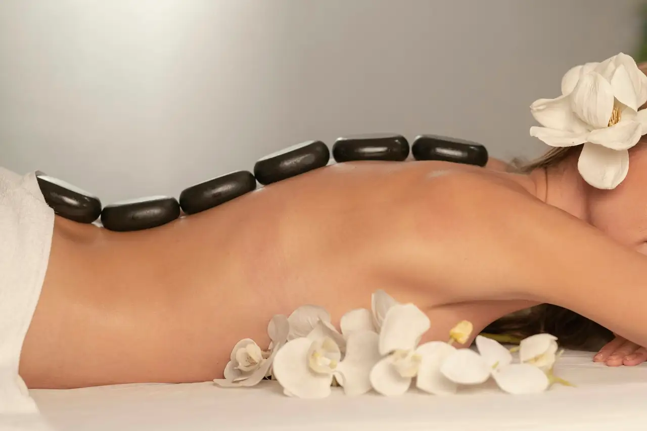 Smooth dark stones lined along a bare back, with white orchids